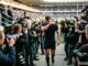 joueur de rugby entouré de photographes et de caméras à la sortie d'un stade
